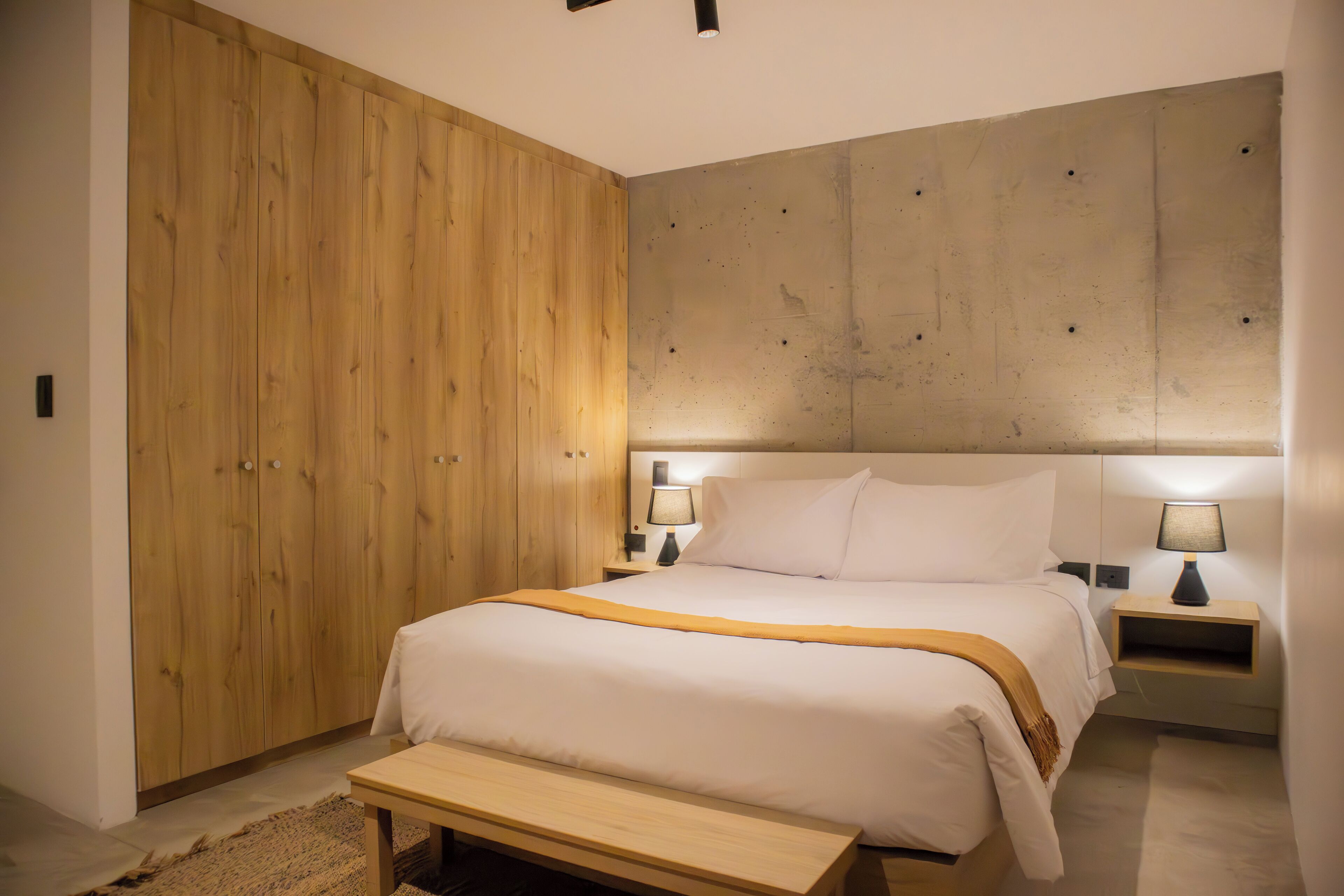 A bedroom with a large bed, wooden wardrobe, and two bedside tables with lamps.