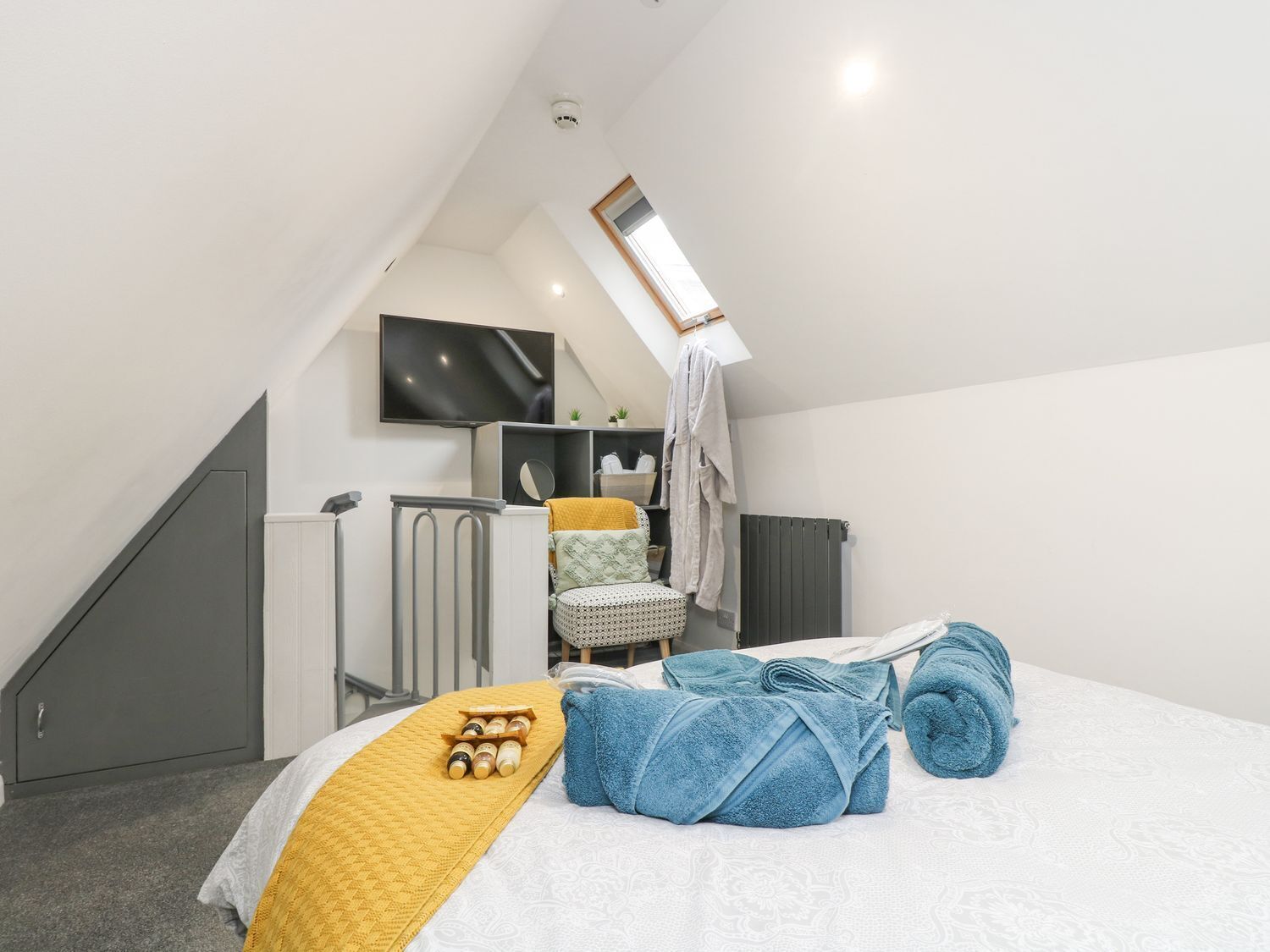 Un dormitorio con cama, televisor, radiador y ventana.