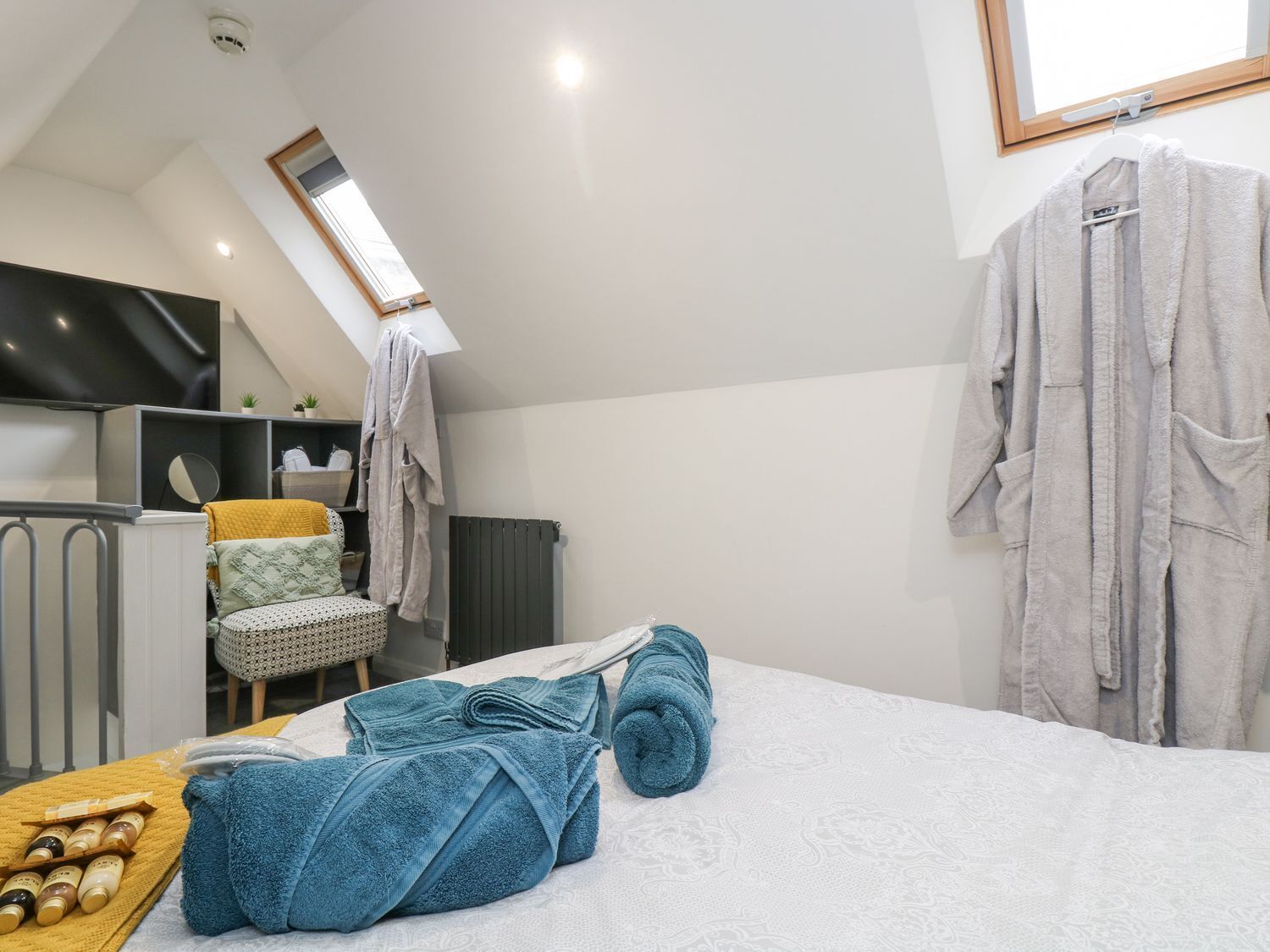 Un dormitorio moderno con una cama, una silla, un radiador y un televisor.