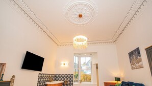 A modern bathroom with a freestanding bathtub, a large mirror, and a chandelier. - Mews Retreat (Camborne)