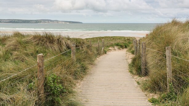 A wooden pathway leading to a beach with a view of the ocean and distant hills. - Mews Retreat (Camborne)