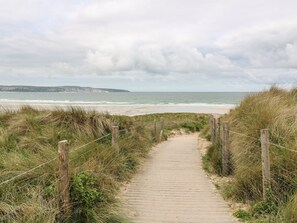 A wooden pathway leading to a beach with a view of the ocean and distant hills. - Mews Retreat (Camborne)