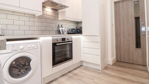 Une cuisine compacte équipée d’un lave-linge, d’un four et d’un réfrigérateur à commande par boutons.