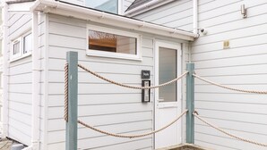 Un bâtiment blanc avec une porte, une petite fenêtre et un clavier de sécurité.