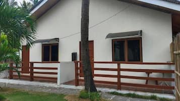 Un edificio de dos pisos con fachada blanca, una valla de madera y una ventana visible.