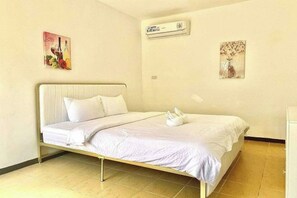 A single-bed room with a metal frame, white bedding, an air conditioning unit, and two wall-mounted artworks. - Dolphin Bay Resort Puerto Galera (Abra de Ilog)