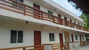 A multi-story building with balconies, windows, and a concrete pathway. - Dolphin Bay Resort Puerto Galera (Abra de Ilog)