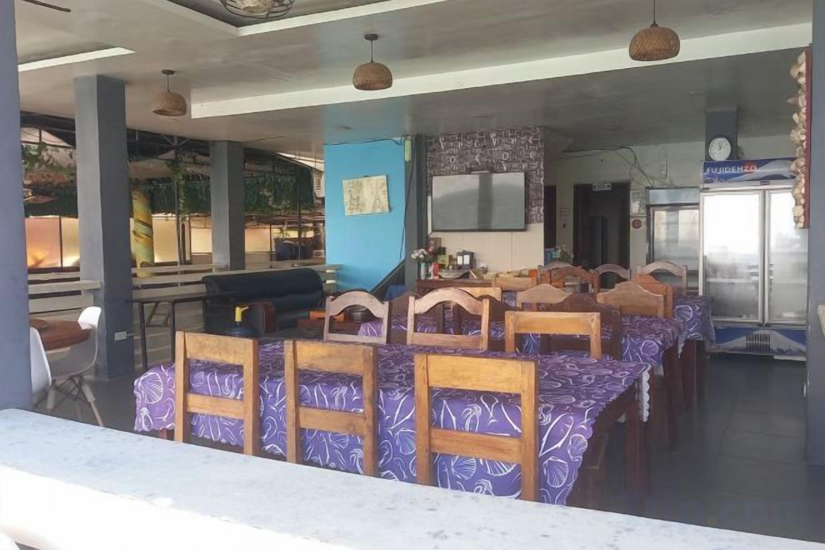 Un restaurante con sillas y mesas de madera, una zona de bar y un refrigerador.