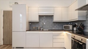 Uma cozinha moderna com armários brancos, micro-ondas, forno e pia.