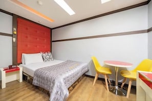 Una camera d'albergo con un letto, un comodino e un piccolo tavolo rotondo con due sedie.