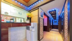 A hotel reception area with a counter, a refrigerator, and a hallway with blue lighting. - Ritz Sillim (Seoul)