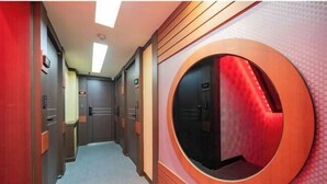 A hotel corridor with a circular window, doors, and a carpeted floor. - Ritz Sillim (Seoul)