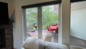 Un salon comprenant un canapé, une cheminée et une porte-fenêtre coulissante donnant sur une terrasse extérieure avec une table et des chaises.