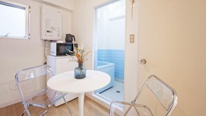 Une cuisine compacte équipée d’un four à micro-ondes, d’un petit placard et d’une table blanche avec des chaises.