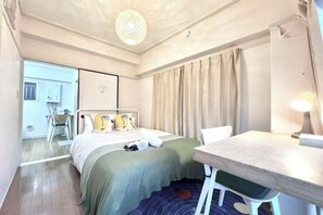 Une chambre d’hôtel équipée d’un lit, d’un bureau, d’une chaise, d’une lampe et offrant une vue sur l’extérieur.