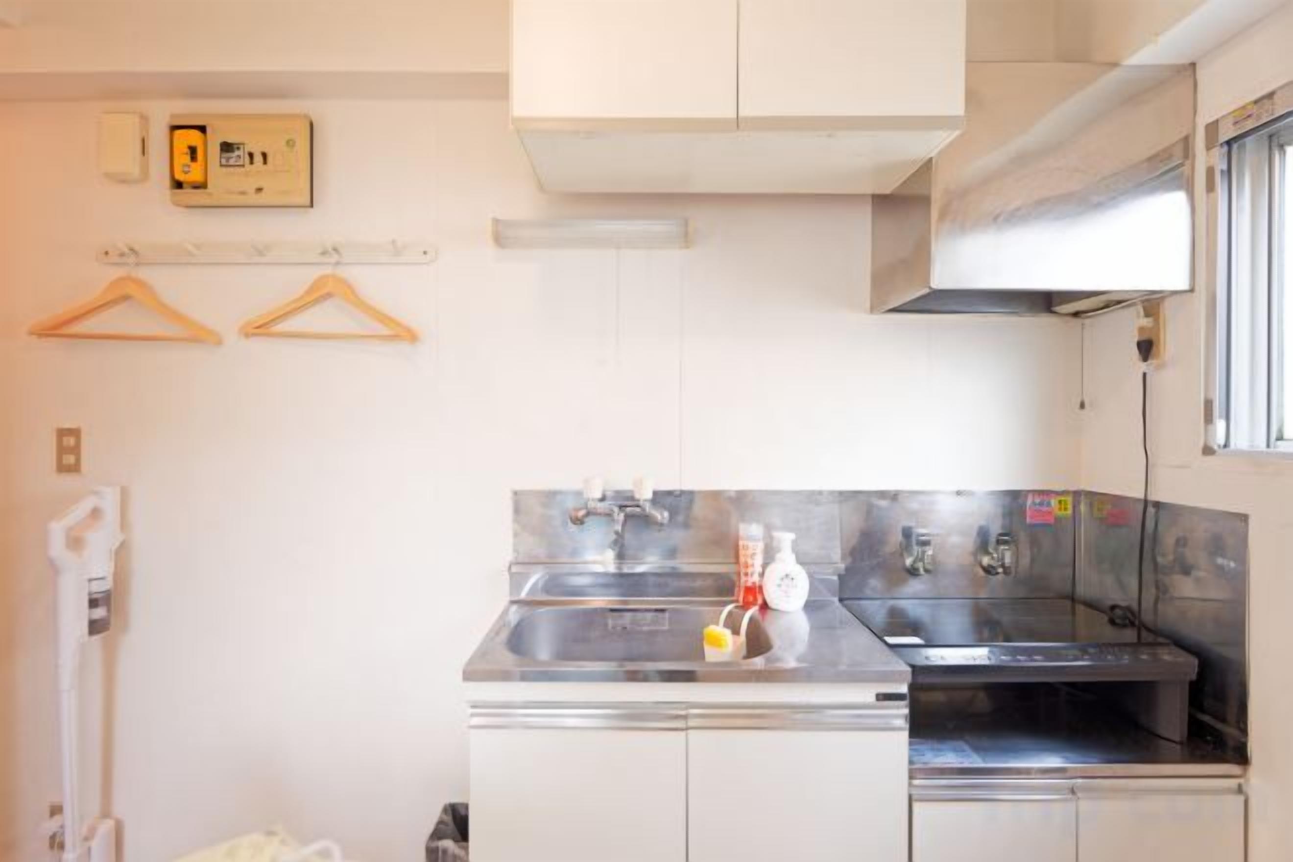 A compact kitchen with a stainless steel sink, a small countertop, and a window above the sink.