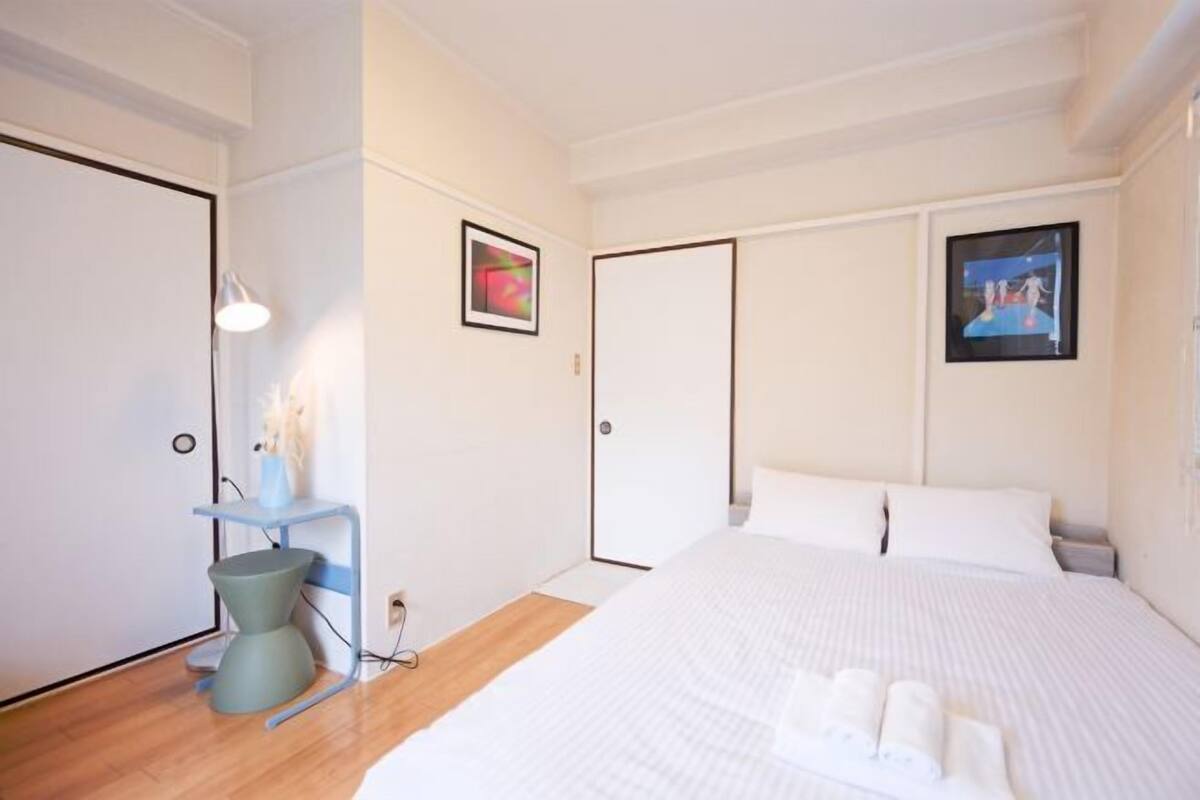 Une chambre d’hôtel avec un lit, des tables de chevet, un bureau et une porte.