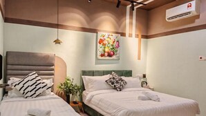 A hotel room with two beds, a green headboard, a floral painting, and a ceiling light fixture. - Kepayan Inn Kinabalu City (Penampang)
