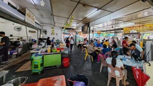 Uma praça de alimentação movimentada, com várias áreas de refeições, mesas e cadeiras.