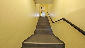 Uma escada com corrimão, que leva a uma porta no topo.