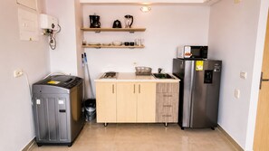Cozinha compacta com máquina de lavar integrada, frigorífico e micro-ondas.
