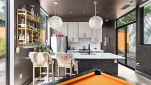 Cozinha moderna com ilha central, banquetas e iluminação pendente.