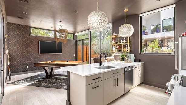 Cozinha moderna com mesa de bilhar, janelas amplas e vista para o exterior.