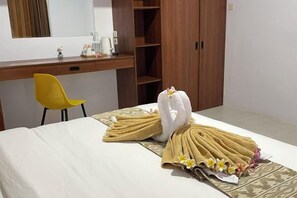 Une chambre d’hôtel avec un lit, un bureau en bois, une chaise jaune et une armoire.