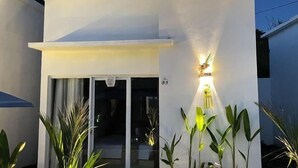Un edificio moderno con fachada blanca, entrada de vidrio e iluminación exterior.