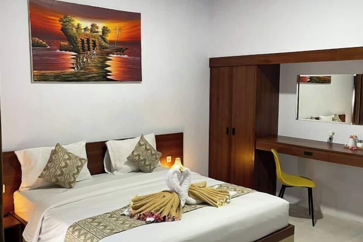 Una habitación de hotel con cama, escritorio, silla y un cuadro en la pared.