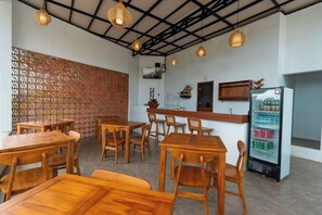 Un interior de restaurante con mesas y sillas de madera, una zona de bar y un refrigerador.