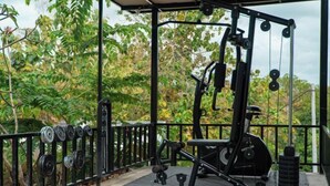 Gimnasio al aire libre con equipo de ejercicio, pesas y una valla de metal.