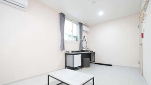 A room with a bed, a desk, a chair, a window with curtains, and a trash bin. - Doksan White (Seoul)