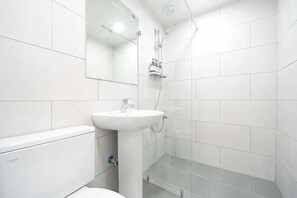 Un bagno con lavandino bianco, specchio e doccia.