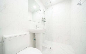 A bathroom with a toilet, sink, and shower. - Doksan White (Seoul)