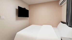 Una camera d'albergo con un letto, una TV a schermo piatto montata a parete e un condizionatore d'aria.