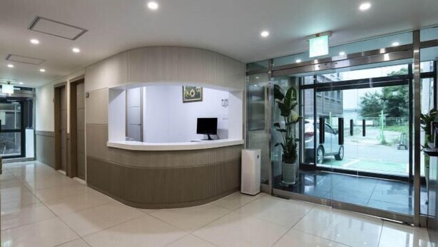 A reception area with a curved counter, a computer monitor, and a glass door leading outside. - Doksan White (Seoul)