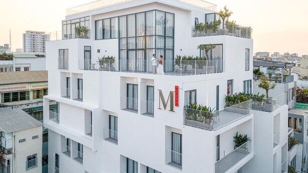 A multi-story building with balconies, large windows, and a prominent 'M' sign. - Express by M Village Ky Dong, a brand of Modern Village Lifestyle (Ho Chi Minh City)