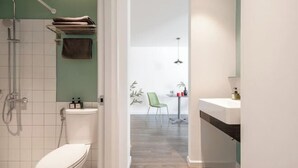 Een moderne badkamer met toilet, douche en wastafel.