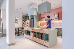 A modern kitchen with a central island, built-in appliances, and a dining area with a table and chairs. - Express by M Village Ky Dong, a brand of Modern Village Lifestyle (Ho Chi Minh City)
