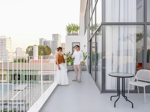 Ein Balkon mit Glasgeländer, einem kleinen Tisch und Stühlen.