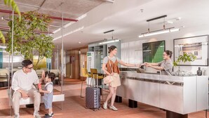 A hotel reception area with a modern design, including a reception desk, seating area, and a plant. - Express by M Village Ky Dong, a brand of Modern Village Lifestyle (Ho Chi Minh City)