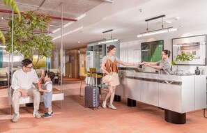 A hotel reception area with a modern design, including a reception desk, seating area, and a plant. - Express by M Village Ky Dong, a brand of Modern Village Lifestyle (Ho Chi Minh City)