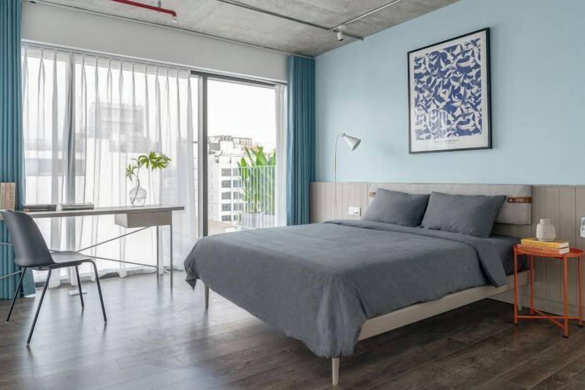 Un dormitorio moderno con cama, escritorio y silla.