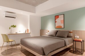 A modern bedroom with a bed, bedside tables, a desk, a chair, and a wall-mounted air conditioner. - Express by M Village Ky Dong, a brand of Modern Village Lifestyle (Ho Chi Minh City)