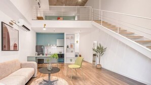 Een modern interieur met een trap, een bank, een eettafel en een keuken.