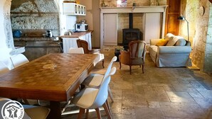 Un interior rústico con chimenea de piedra, mesa de comedor de madera y una zona de estar acogedora.