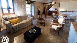 Una sala de estar rústica con un sofá, sillones, una mesa de centro y un comedor con mesa y sillas.