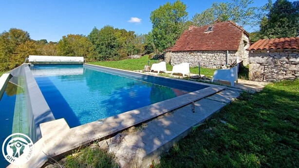 Una piscina con una casa de piedra al fondo.
