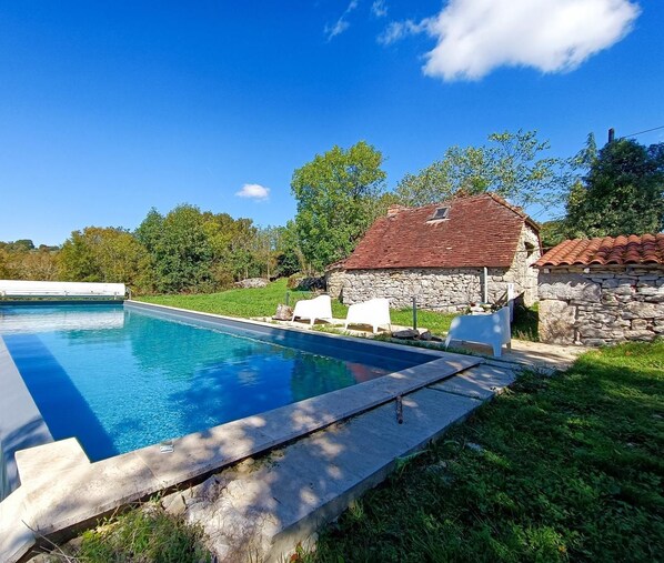 Une piscine avec une maison en pierre en arrière-plan.